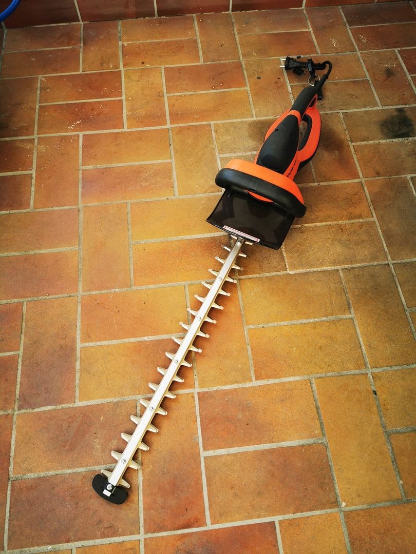 Eine elektrische Heckenschere liegt auf dem Boden