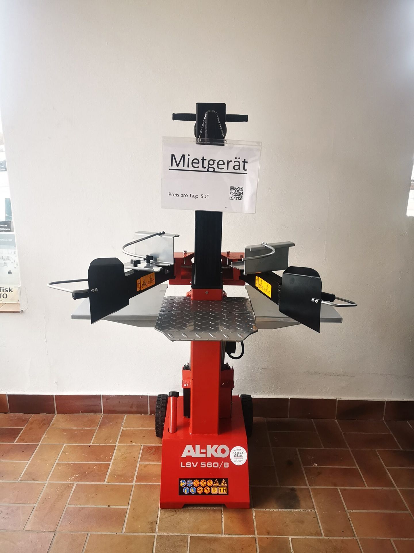 Ein roter Holzspalter steht auf dem Boden.